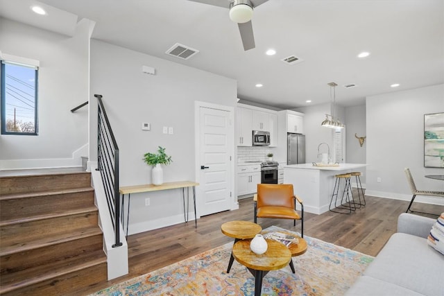 living area featuring recessed lighting, visible vents, stairway, dark wood-type flooring, and a ceiling fan