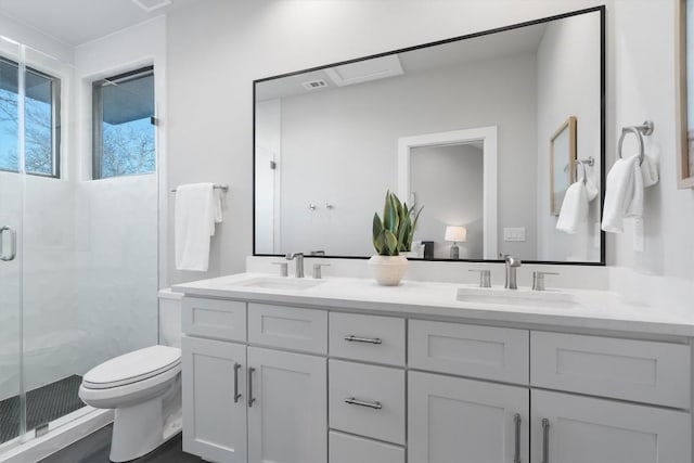 bathroom featuring a stall shower, a sink, toilet, and double vanity