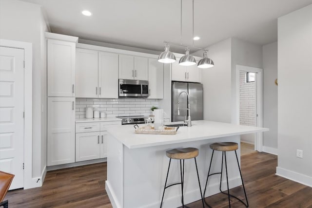 5403 Duval St Unit 2, Austin, TX 78751 - kitchen with appliances with stainless steel finishes, backsplash, white cabinets, a center island with sink, and a kitchen breakfast bar