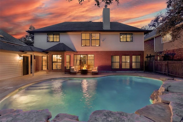 pool at dusk featuring an outdoor hangout area, a patio, fence, and a fenced in pool