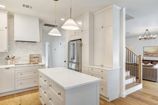 kitchen with tasteful backsplash, electric cooktop, visible vents, high quality fridge, and light wood-type flooring