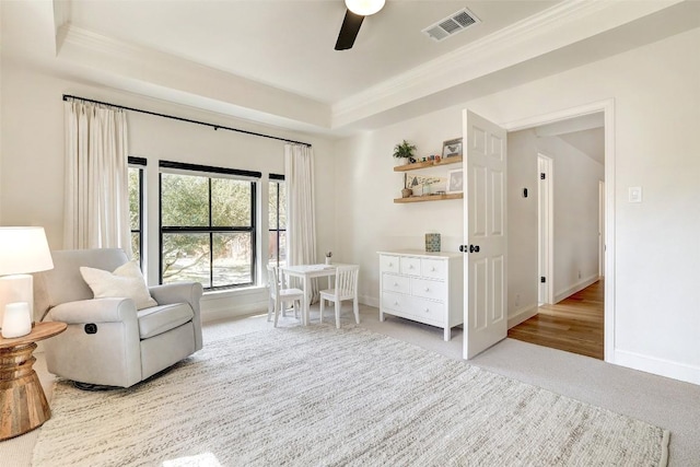 sitting room featuring a tray ceiling, carpet, visible vents, a ceiling fan, and baseboards