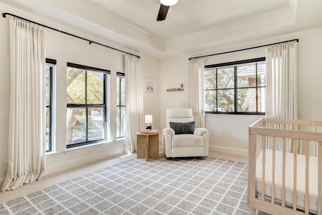 bedroom with a crib, baseboards, a raised ceiling, ornamental molding, and carpet flooring