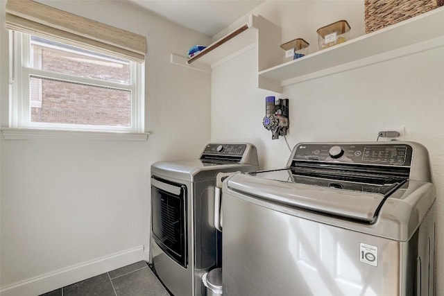 washroom featuring washer and dryer, laundry area, dark tile patterned flooring, and baseboards