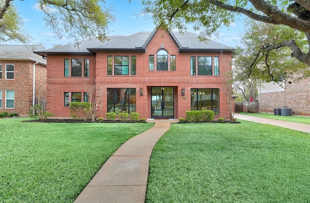 view of front of property with brick siding, a front lawn, and roof with shingles