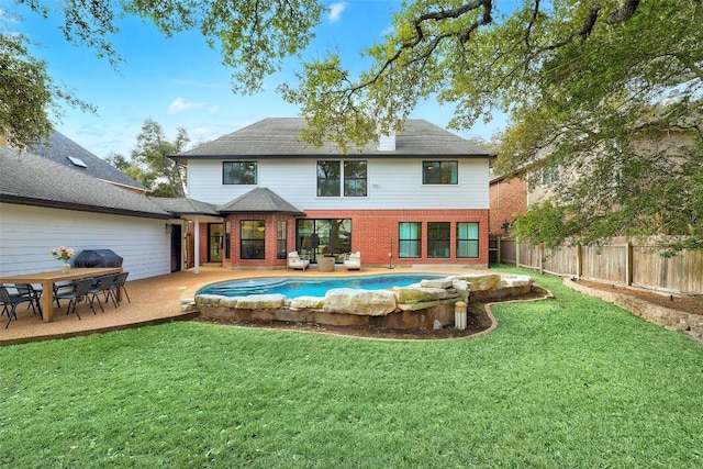 rear view of property with a patio, brick siding, fence, a yard, and a fenced in pool