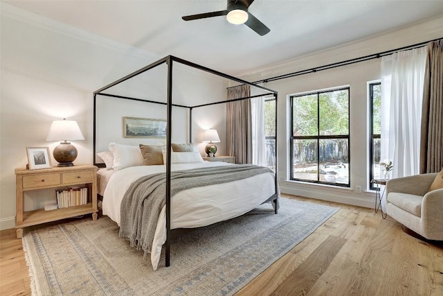 bedroom featuring light wood-type flooring, baseboards, a ceiling fan, and crown molding