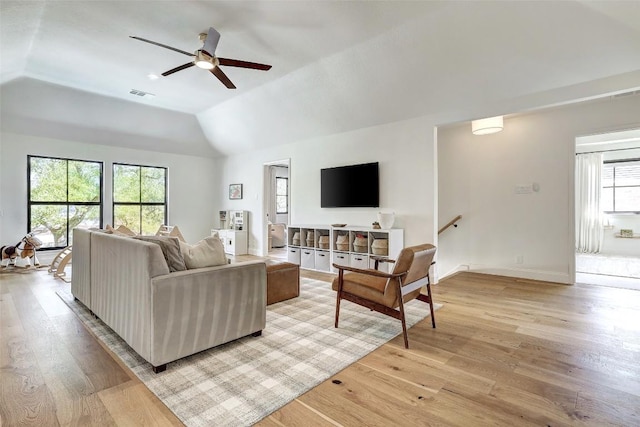 living room featuring light wood-style floors, visible vents, vaulted ceiling, and baseboards