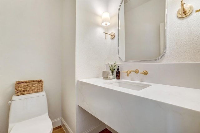 bathroom with baseboards, vanity, and toilet