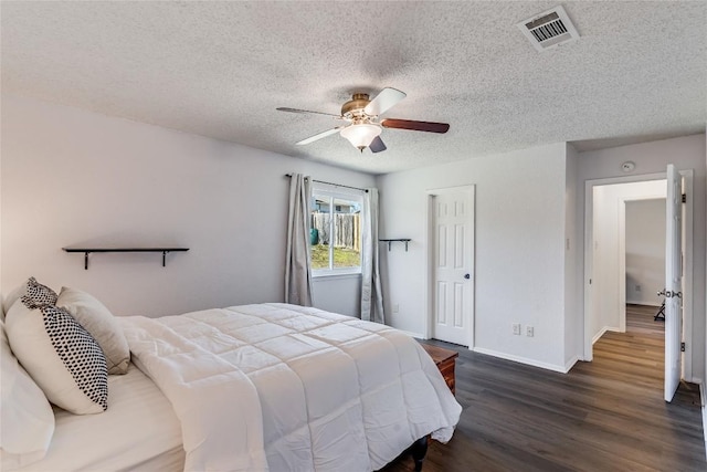 bedroom with a textured ceiling, ceiling fan, dark wood-type flooring, visible vents, and baseboards