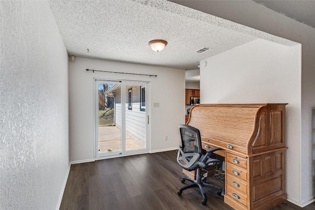 unfurnished office with visible vents, a textured wall, dark wood-type flooring, a textured ceiling, and baseboards