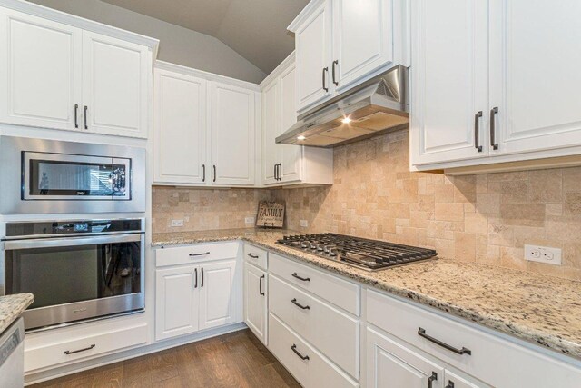 409 Flying Orchid Dr, San Marcos, TX 78666 - kitchen with appliances with stainless steel finishes, under cabinet range hood, vaulted ceiling, and white cabinets