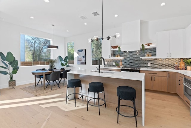 4402 Garnett St Unit 1, Austin, TX 78745 - kitchen with open shelves, a sink, light countertops, light wood-type flooring, and recessed lighting