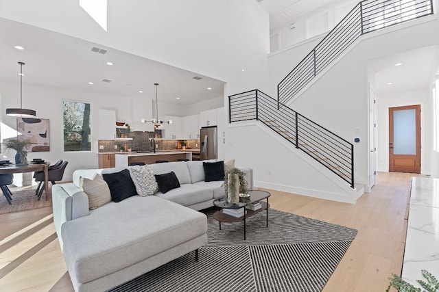 4402 Garnett St Unit 1, Austin, TX 78745 - living area with stairway, light wood-style flooring, a high ceiling, and recessed lighting