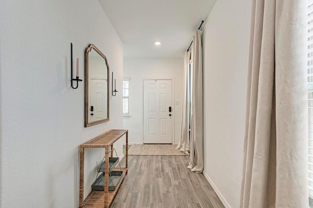 hallway with light wood finished floors, baseboards, and recessed lighting