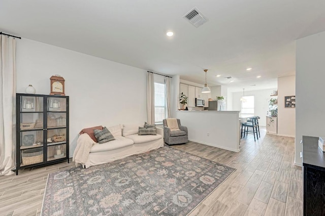 living room with light wood finished floors, baseboards, visible vents, and recessed lighting