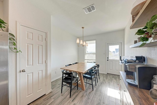 dining room featuring light wood-style floors, visible vents, and baseboards