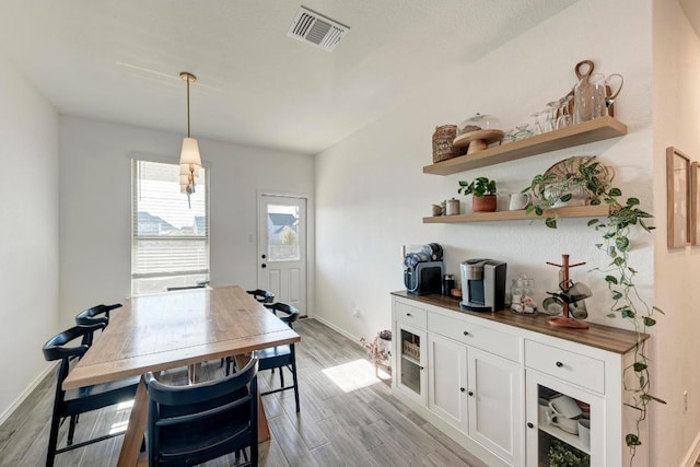 dining space with light wood finished floors, baseboards, and visible vents