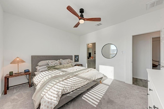 bedroom with ceiling fan, visible vents, connected bathroom, and light colored carpet