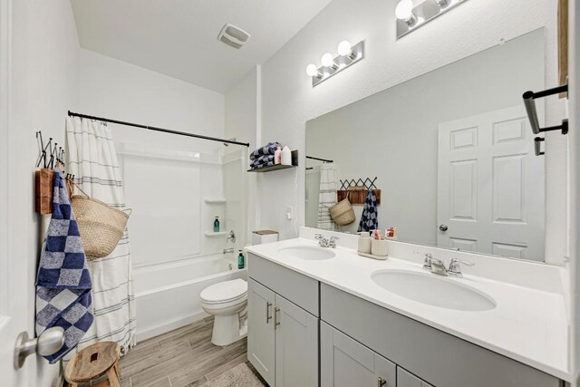 bathroom featuring toilet, visible vents, a sink, and wood finished floors