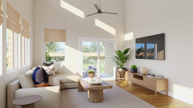 living room featuring ceiling fan, a high ceiling, and wood finished floors