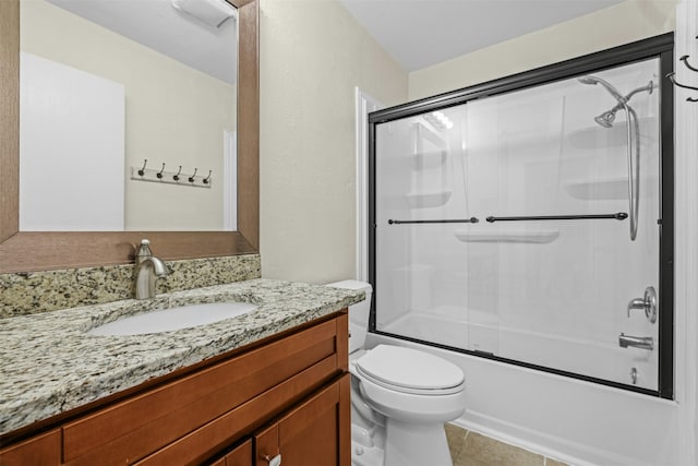 bathroom featuring enclosed tub / shower combo, toilet, vanity, and tile patterned floors