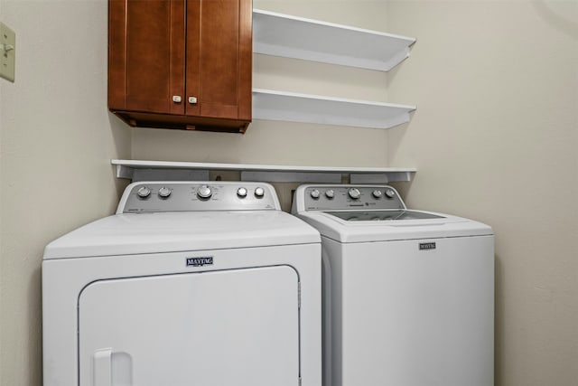 washroom with cabinet space and washing machine and clothes dryer