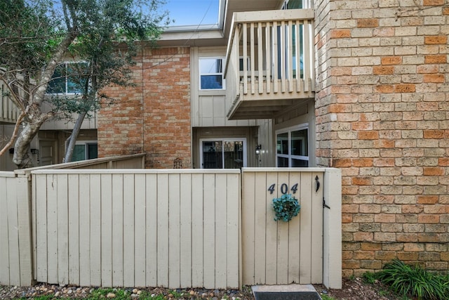 exterior space featuring brick siding, fence, and a balcony