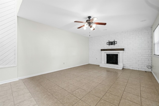 unfurnished living room with light tile patterned floors, a brick fireplace, ceiling fan, brick wall, and baseboards