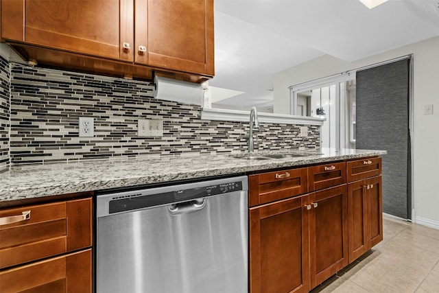 kitchen featuring a sink, tasteful backsplash, light stone counters, and stainless steel dishwasher