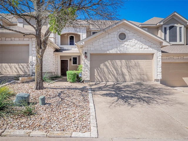 view of front facade with an attached garage, a shingled roof, concrete driveway, stone siding, and stucco siding