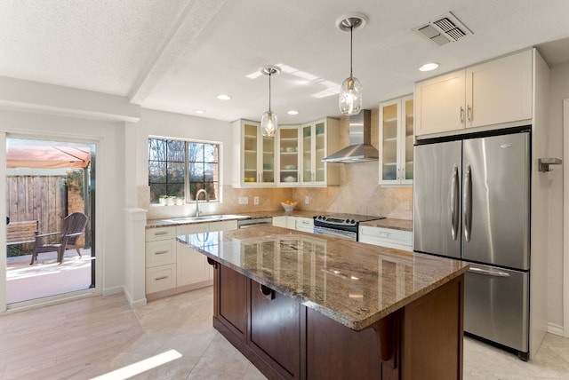 kitchen featuring stainless steel appliances, a sink, visible vents, decorative backsplash, and wall chimney exhaust hood