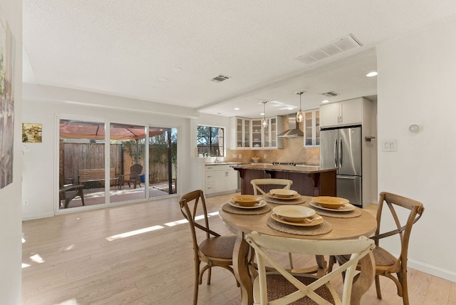 dining area with light wood finished floors, baseboards, and visible vents