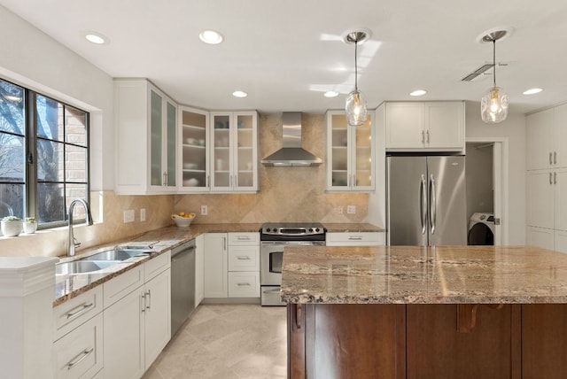 kitchen with washer / dryer, tasteful backsplash, stainless steel appliances, wall chimney range hood, and a sink