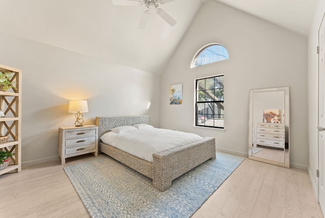 bedroom with high vaulted ceiling, light wood-type flooring, a ceiling fan, and baseboards