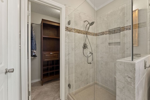 full bath featuring tile patterned flooring, a walk in closet, a textured ceiling, crown molding, and a shower stall