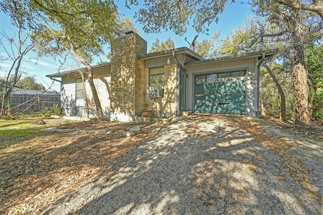 view of front of house featuring aphalt driveway, a chimney, an attached garage, and fence