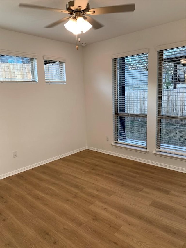 unfurnished room with a ceiling fan, plenty of natural light, baseboards, and wood finished floors