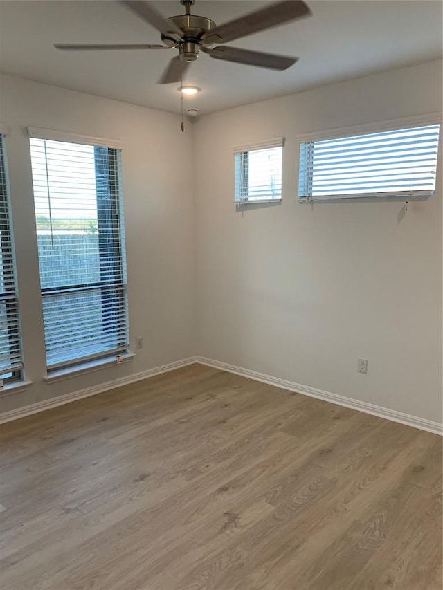 spare room with baseboards, light wood finished floors, and a healthy amount of sunlight