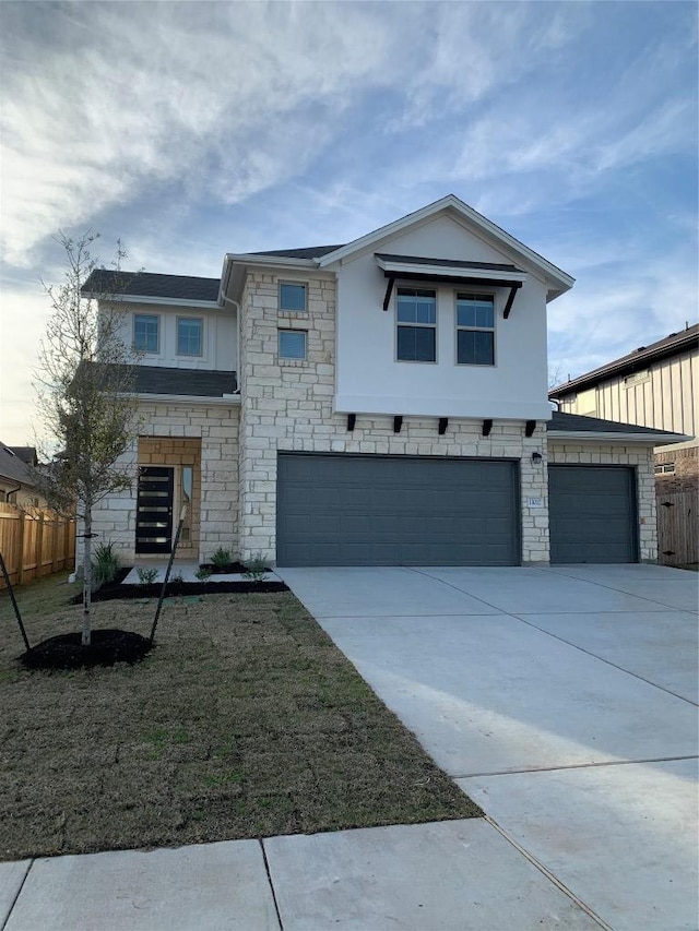 view of front facade featuring a garage, driveway, stone siding, and fence