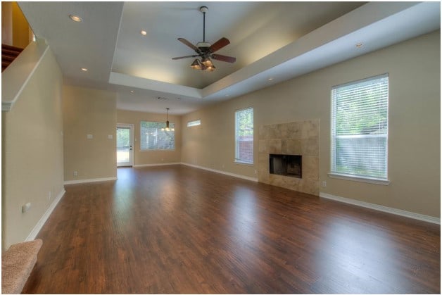 unfurnished living room featuring wood finished floors, a tray ceiling, a tile fireplace, and baseboards