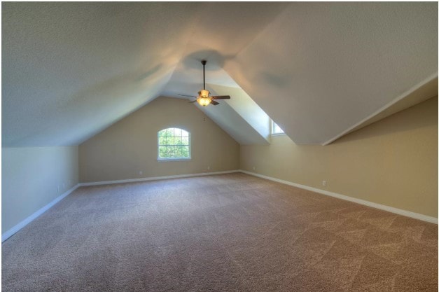 bonus room with lofted ceiling, ceiling fan, carpet flooring, and baseboards