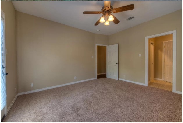 unfurnished bedroom with ceiling fan, carpet, visible vents, and baseboards