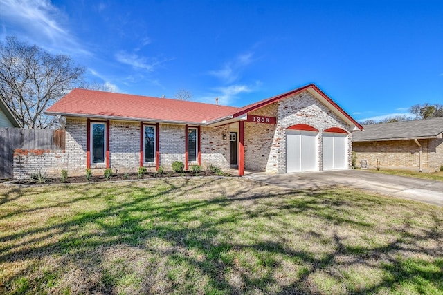 view of front of home with concrete driveway, an attached garage, fence, a front lawn, and brick siding