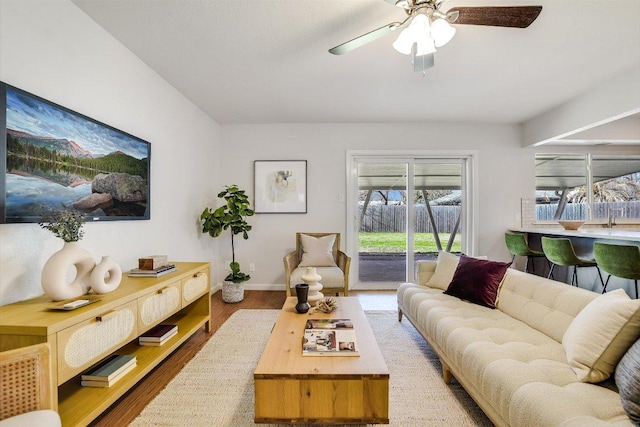 living area with a ceiling fan, baseboards, and wood finished floors