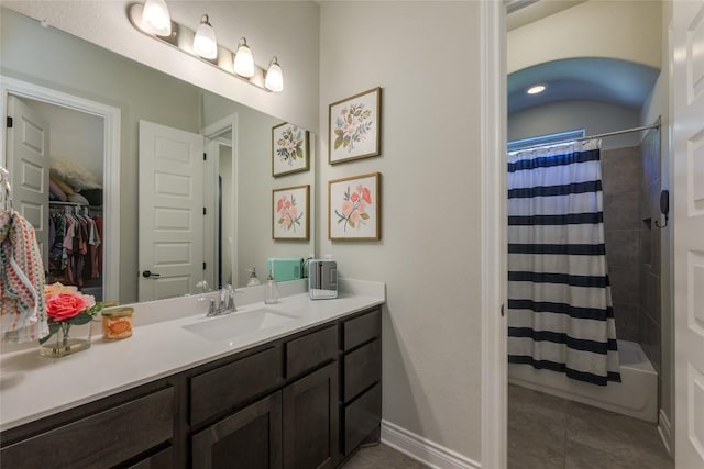 bathroom featuring tile patterned floors, baseboards, vanity, shower / tub combo with curtain, and a spacious closet