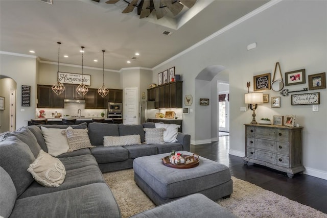 living area with arched walkways, a ceiling fan, recessed lighting, and dark wood-type flooring