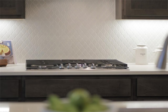 interior details featuring light countertops, stainless steel gas stovetop, backsplash, and dark brown cabinetry