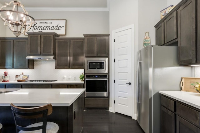 kitchen with light countertops, ornamental molding, dark brown cabinets, and stainless steel appliances