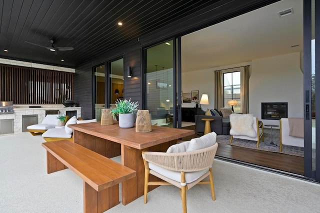 view of patio with outdoor dining area, an outdoor kitchen, visible vents, and a ceiling fan